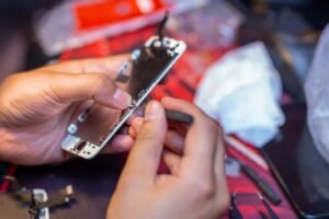 A man is repairing a mobile phone. In the frame, his hands and details of the device. repair shop